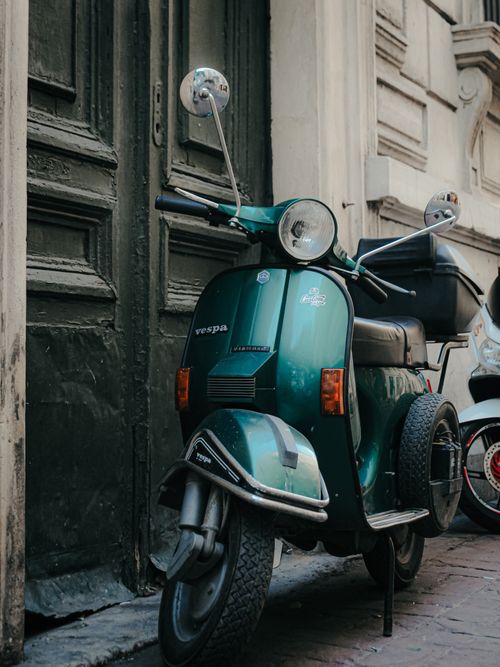 Free Vintage green Vespa scooter parked beside rustic doors on a city street in İstanbul, Türkiye. Stock Photo