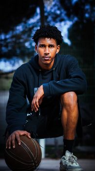 Confident young athlete crouching with basketball outdoors in Leiria, Portugal.