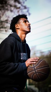 Young man intensely focused while preparing to shoot a basketball outdoors.