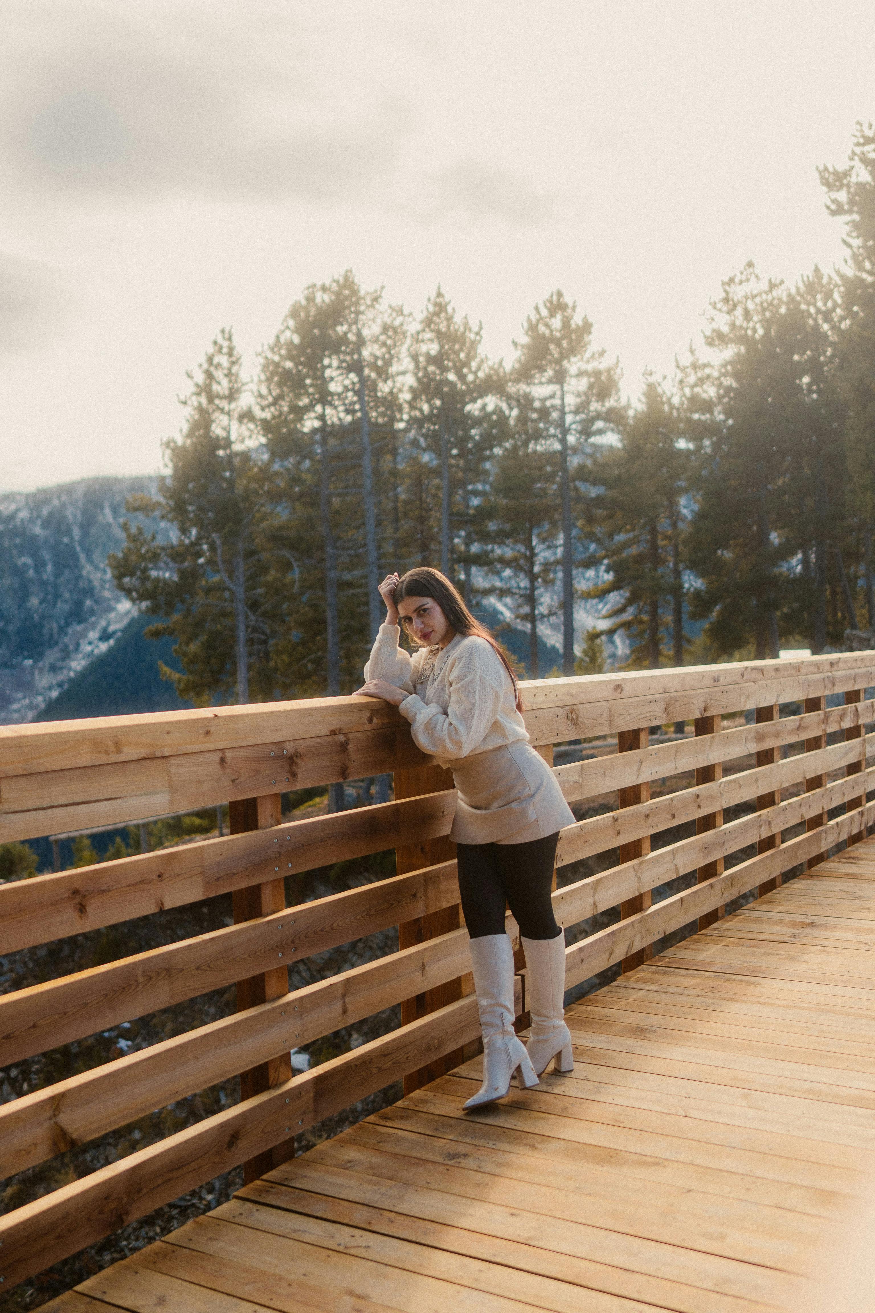 woman standing on wooden footbridge in forest