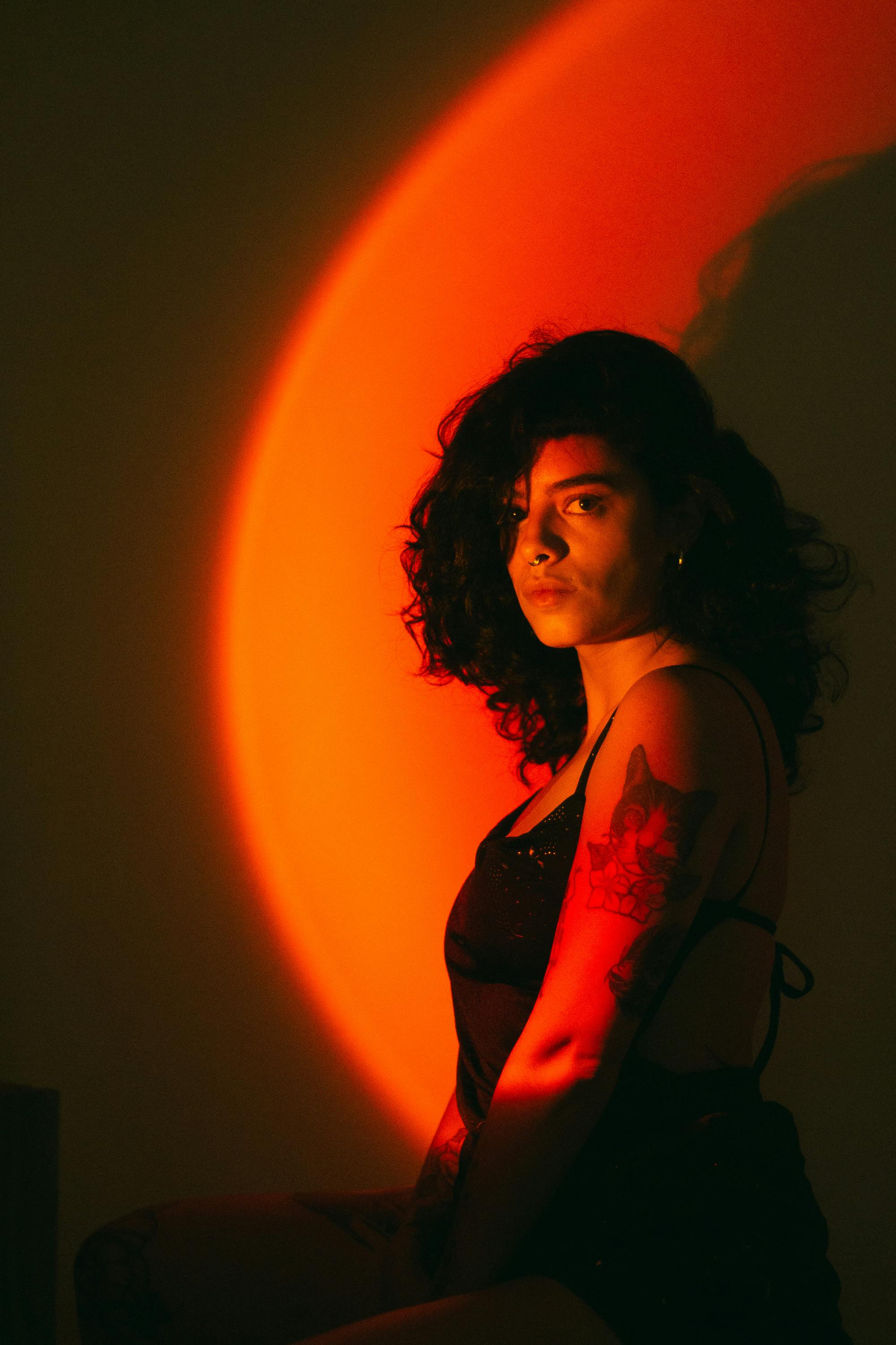 A captivating portrait of a woman in warm light, showcasing tattoos and a pensive expression.