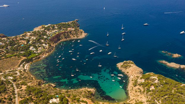 Stunning aerial view of Ibiza's coastline with turquoise waters and yachts.