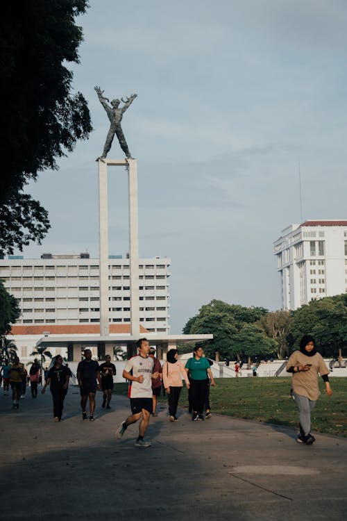 People Walking on Pavement with a Monument in the Background