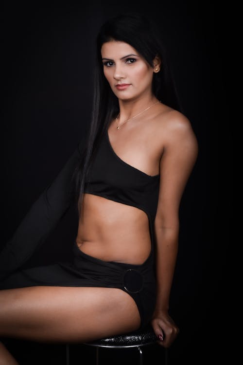 A woman in black top and black shorts sitting on a stool