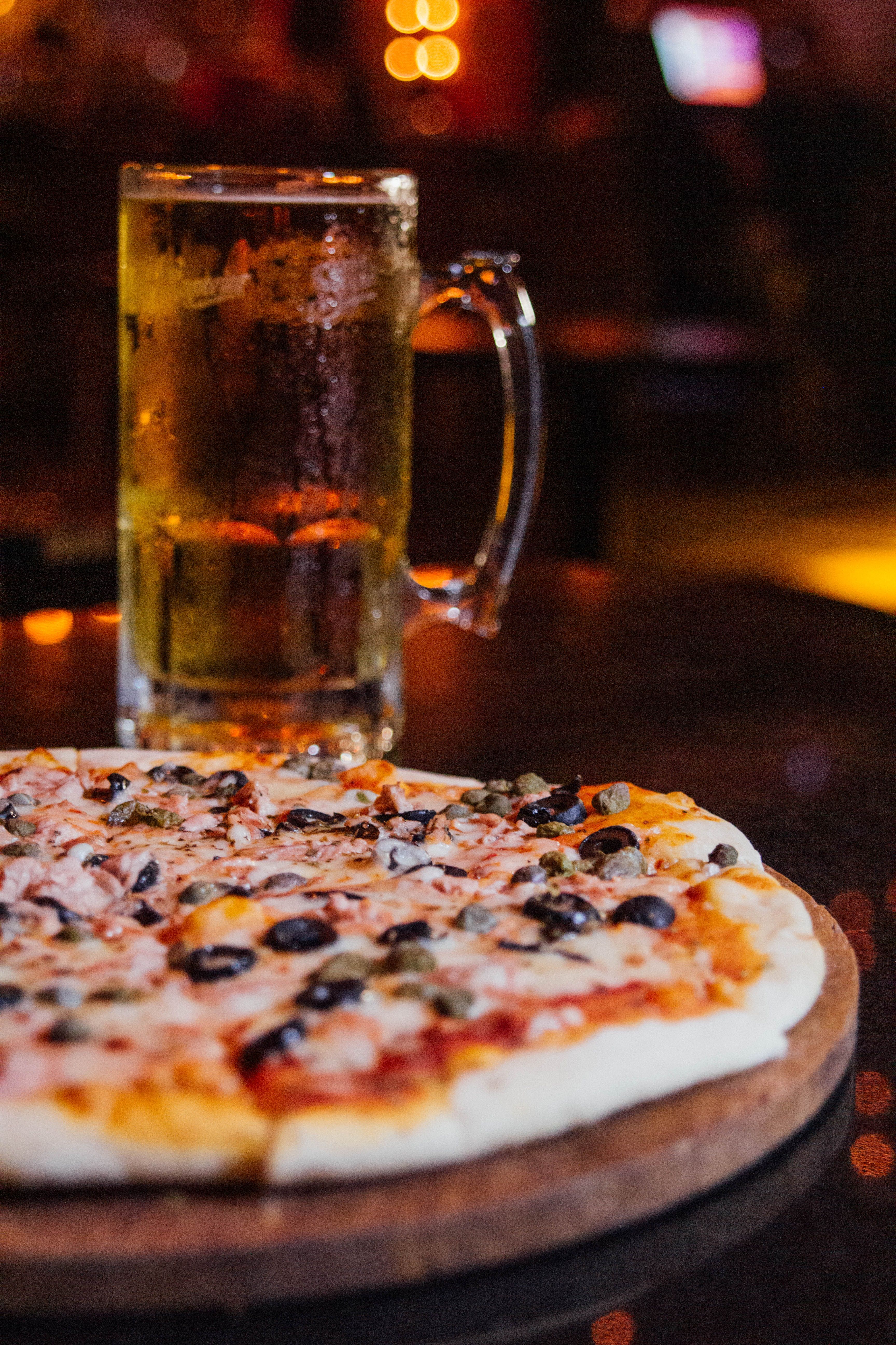 close-up of a tavern-style pizza with a beer