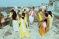 Group of people in traditional attire dancing on a rooftop during a cultural celebration.