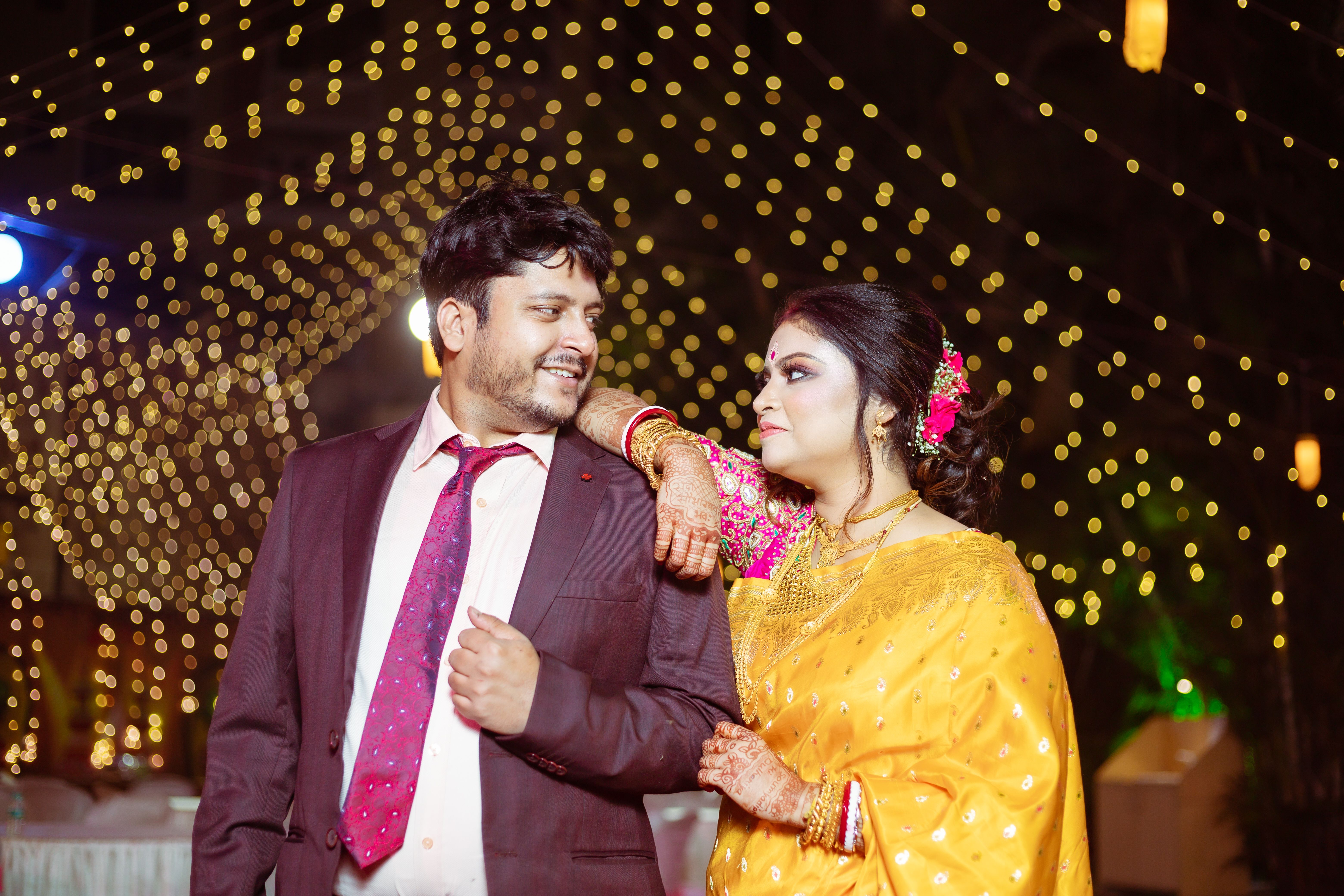 A couple enjoys a festive night under twinkling lights, showcasing elegance and cultural attire.
