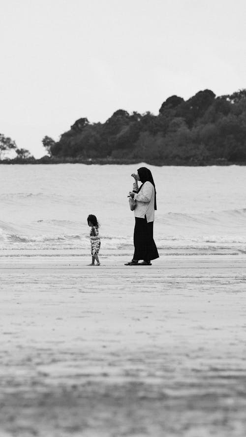 Free A woman and child walking on the beach Stock Photo