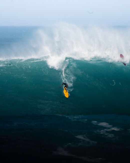 Catch the intense moment of a surfer mastering huge waves at Waimea Bay, Hawaii. Adventure captured.