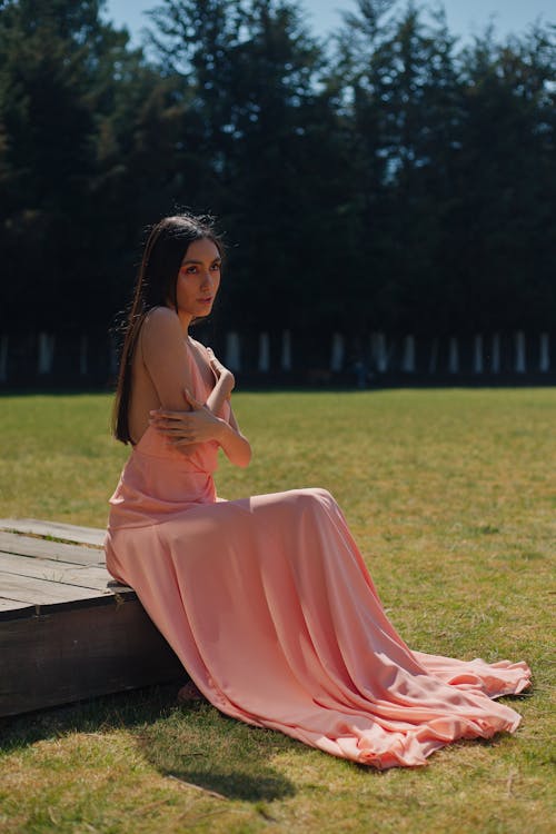 A woman in a pink dress sitting on a bench