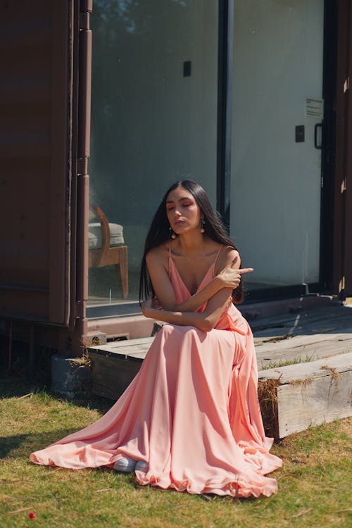 Young Woman in a Pink Dress Sitting on a Wooden Step 