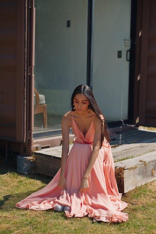 Brunette Woman in Pink Dress Sitting and Looking Down