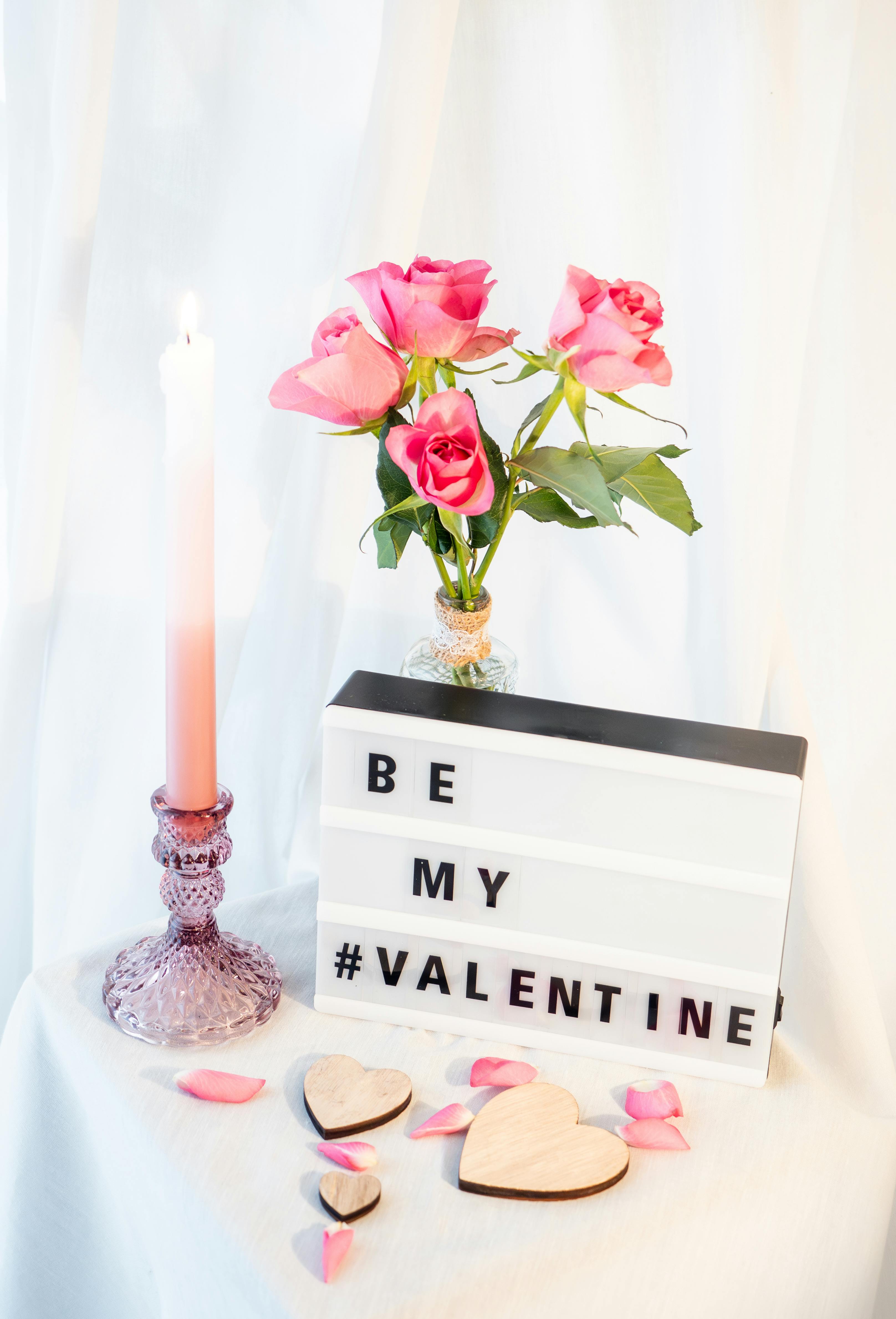 Romantic still life with pink roses, candle, hearts, and Valentine message.