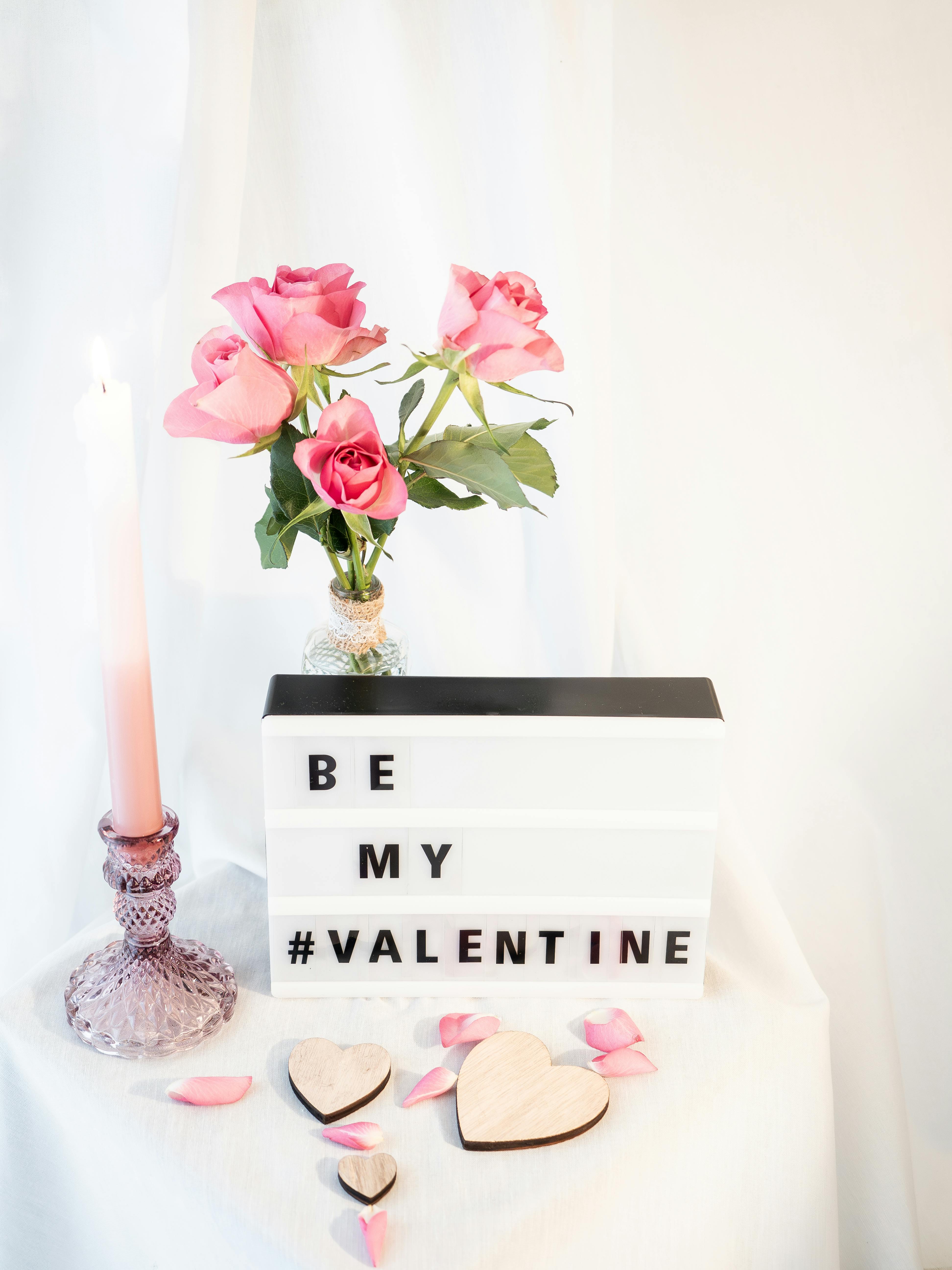 Elegant Valentine's Day scene with roses, candle, and "Be My Valentine" sign.