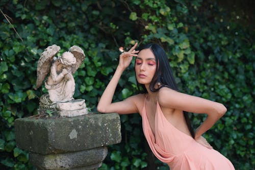 A woman in a pink dress posing next to a statue