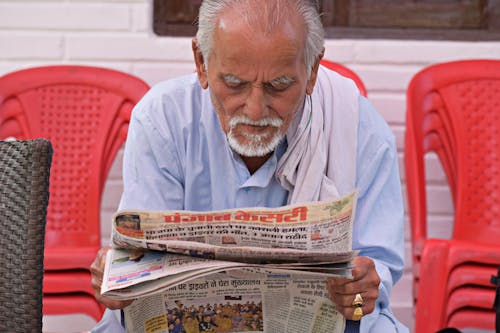 Elderly Man Sitting and Reading a Newspaper 