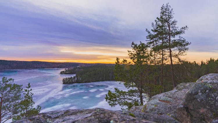 Rocky Hill Over Forest And Lake At Sunset