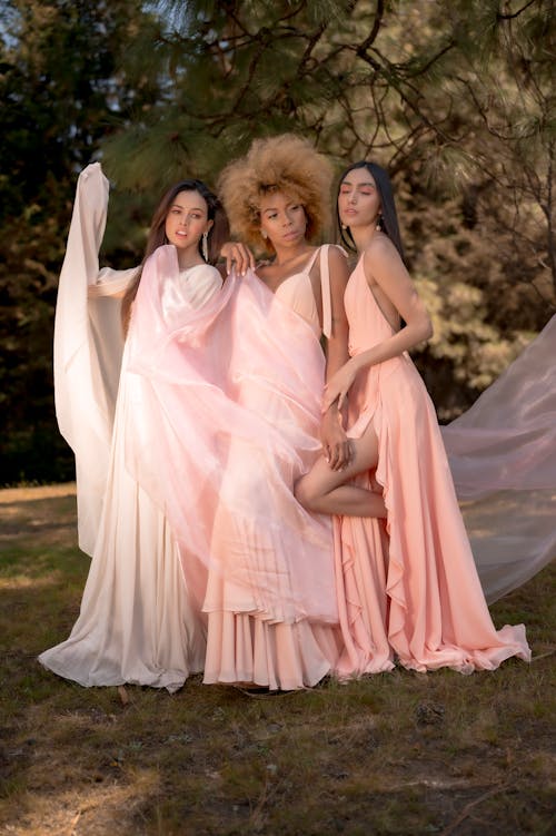 Three women in pink dresses pose for a photo