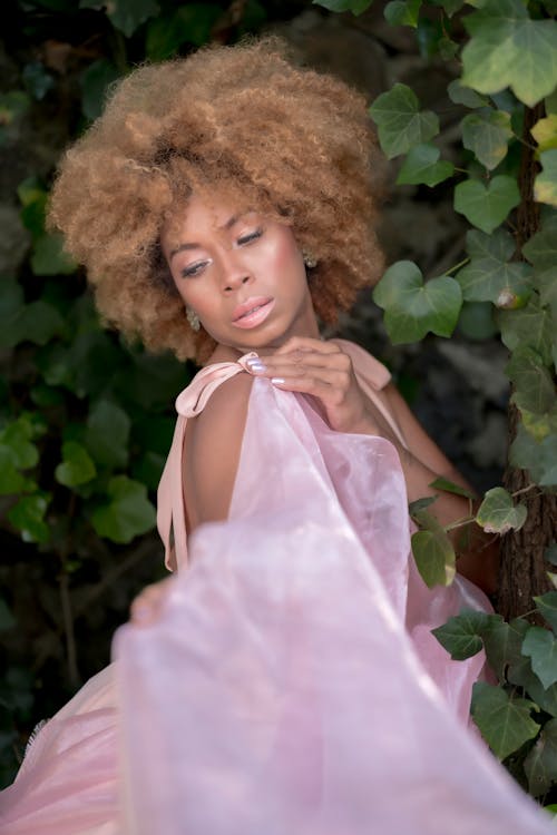 A woman with an afro wearing a pink dress
