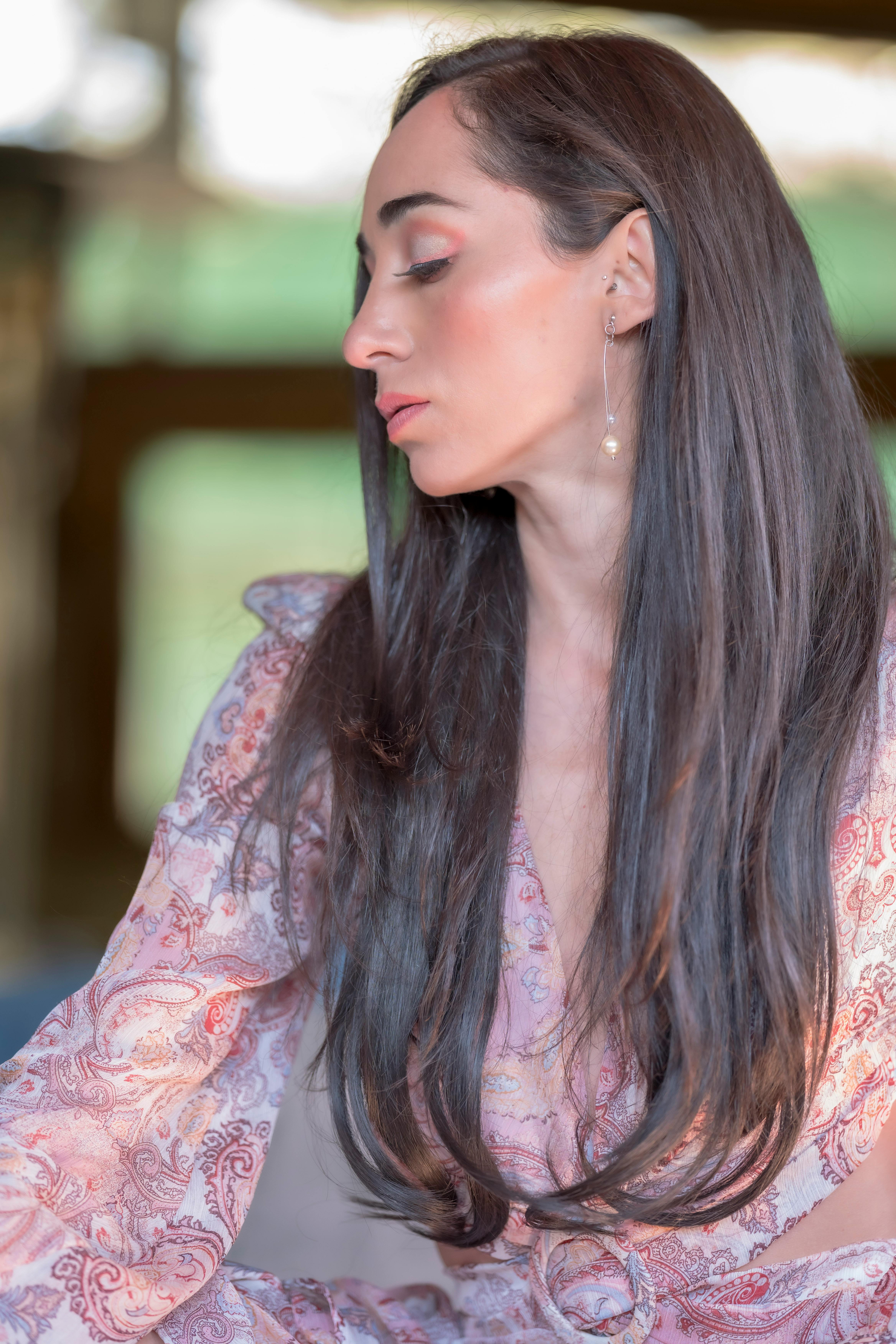 Elegant woman with long dark hair wearing a floral dress, eyes closed in a profile pose.