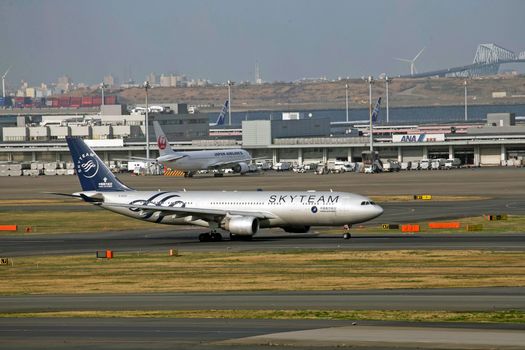 SkyTeam aircraft taxiing on a runway with a bustling airport backdrop.