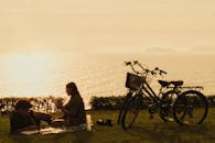 在秘鲁利马，一对夫妇在日落时分骑着自行车享受海边的美景