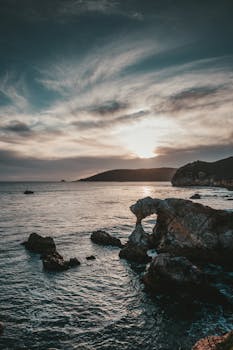阿维拉海滩的日落迷人，岩石海岸与戏剧性的天空相映成趣