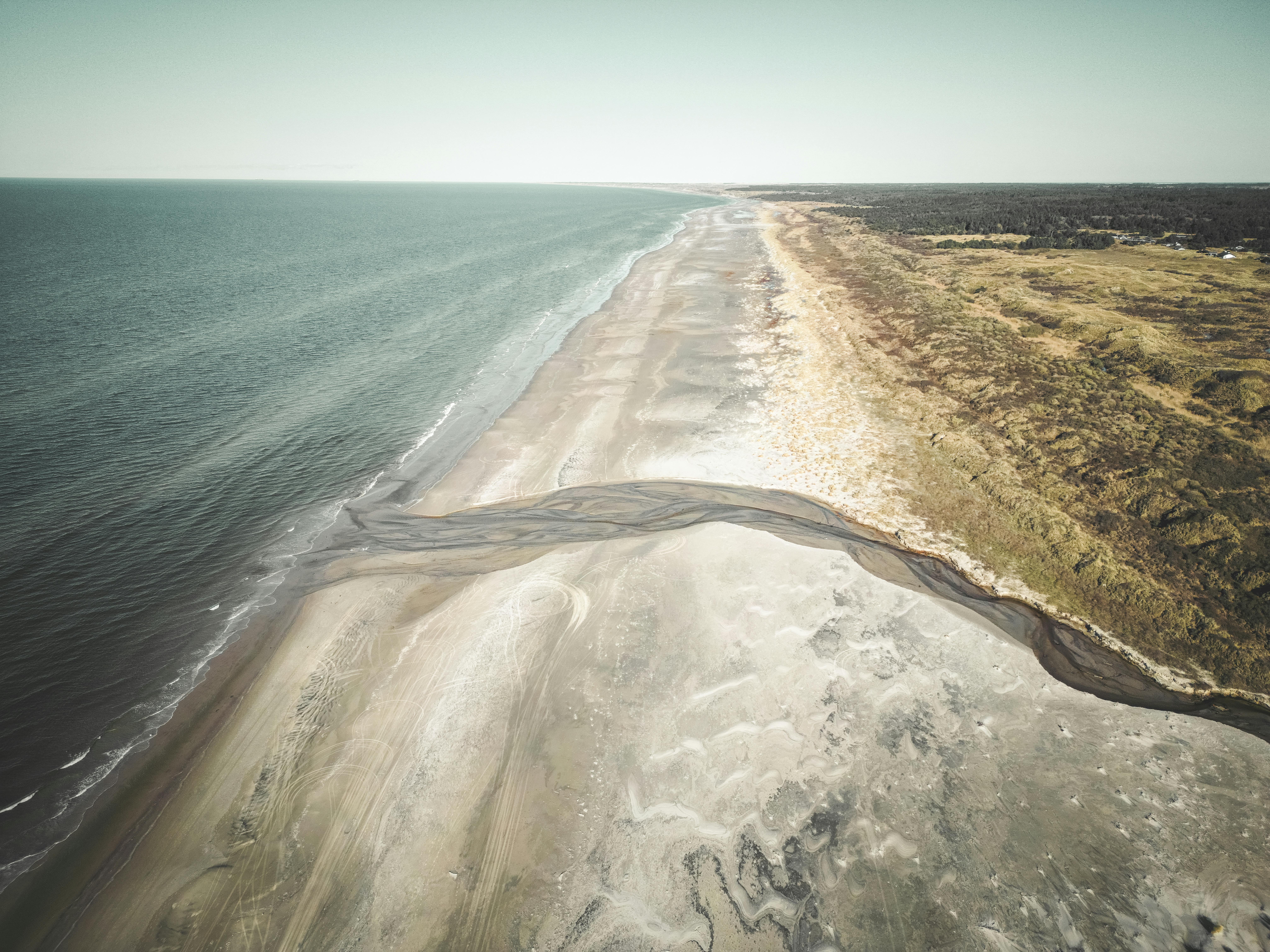 A stunning aerial view of Bindslev Beach, Denmark, showcasing the coastal landscape with sea and sand.