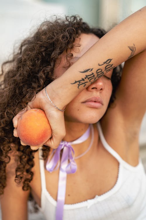 Portrait of Woman Holding Peach in Arm over Face