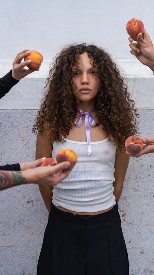 People Hands Holding Peaches over Woman in Tank Top