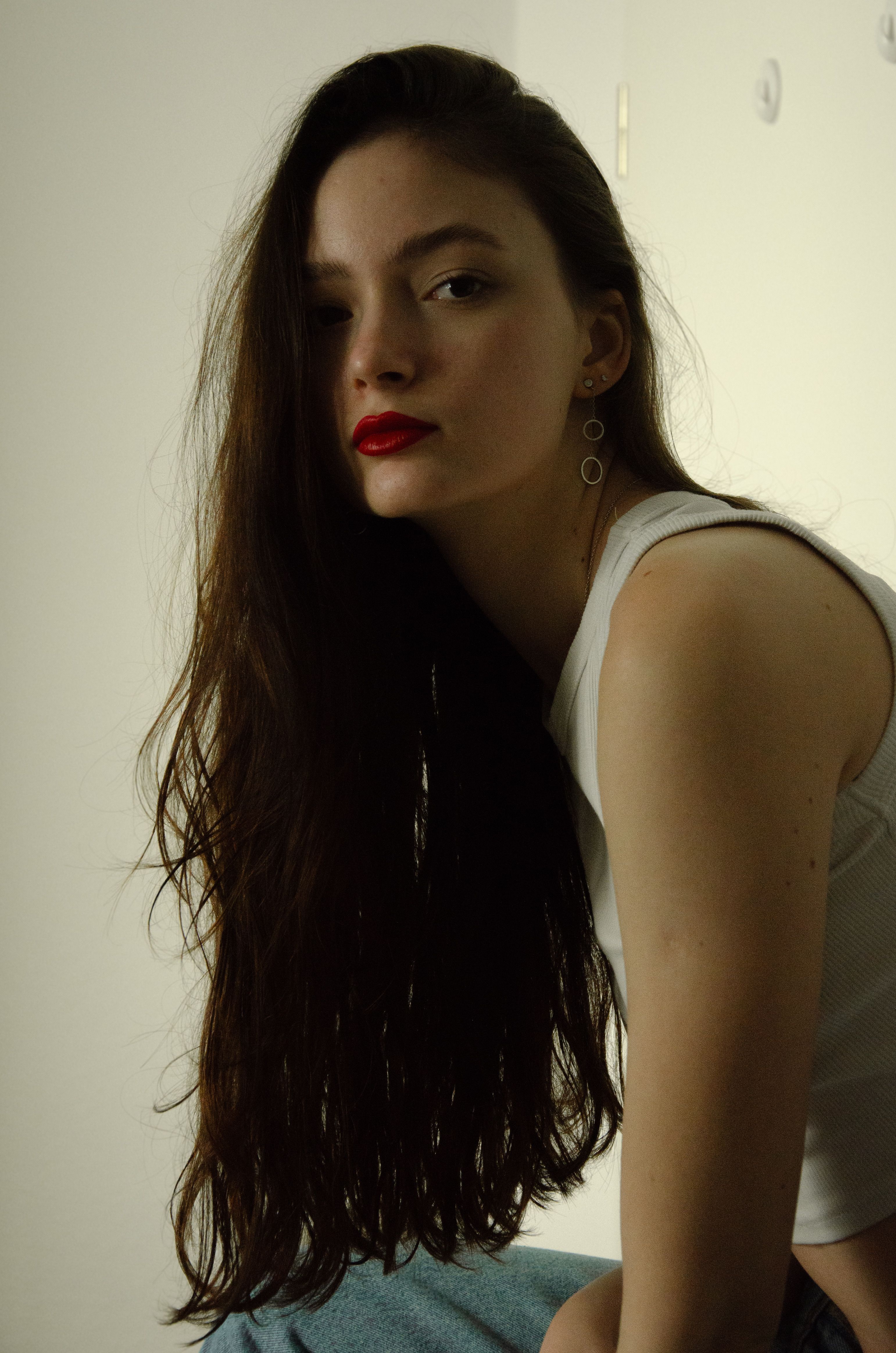 A fashionable woman with long hair and red lipstick, wearing a crop top. Portrait shot.