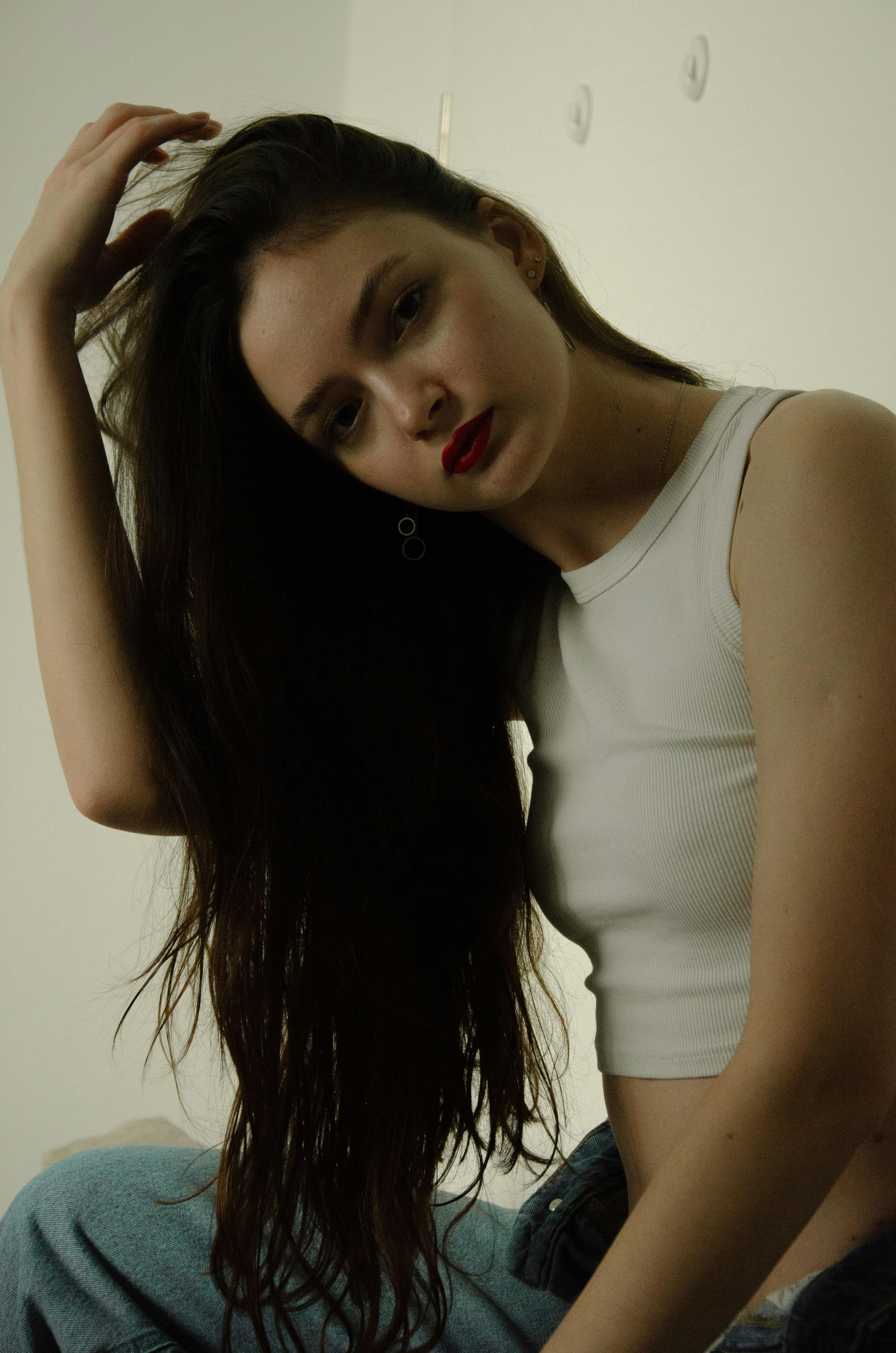 Portrait of a stylish woman with long hair and red lipstick wearing a white crop top indoors.