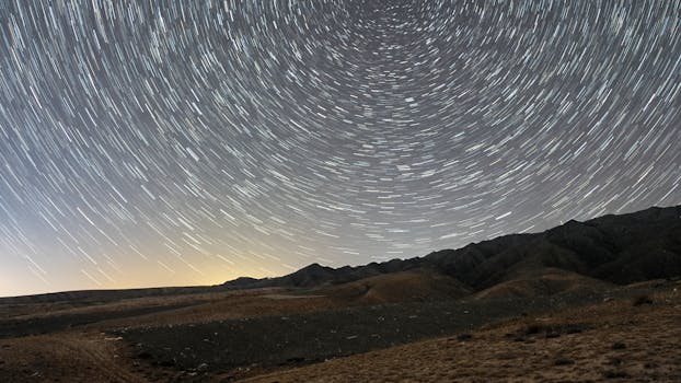 Stunning long-exposure photo capturing mesmerizing star trails over isolated mountain range at night.