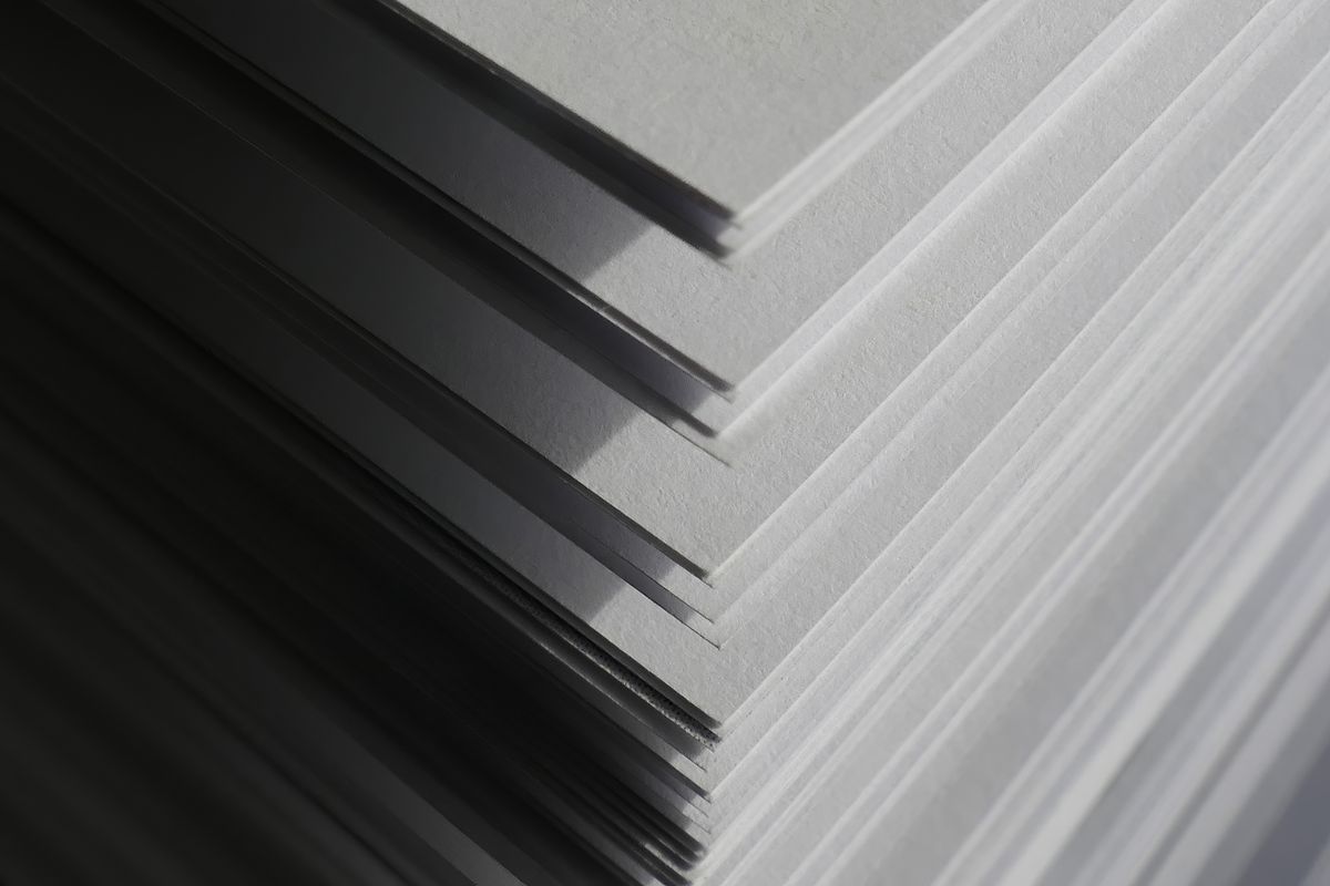 Close-up of stacked paper sheets casting geometric shadows — Michaela St on Pexels