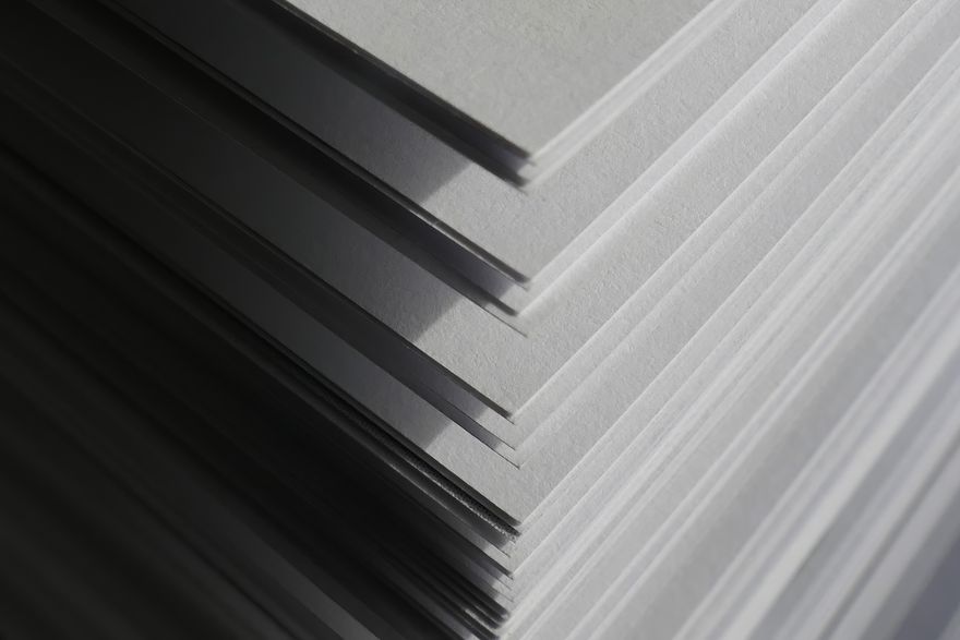Stacked sheets of white paper in raking light — photo by Michaela St on Pexels