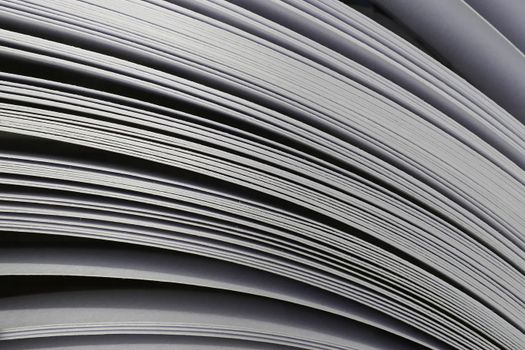 Close-up of curved layers of stacked paper sheets showcasing texture and lines.