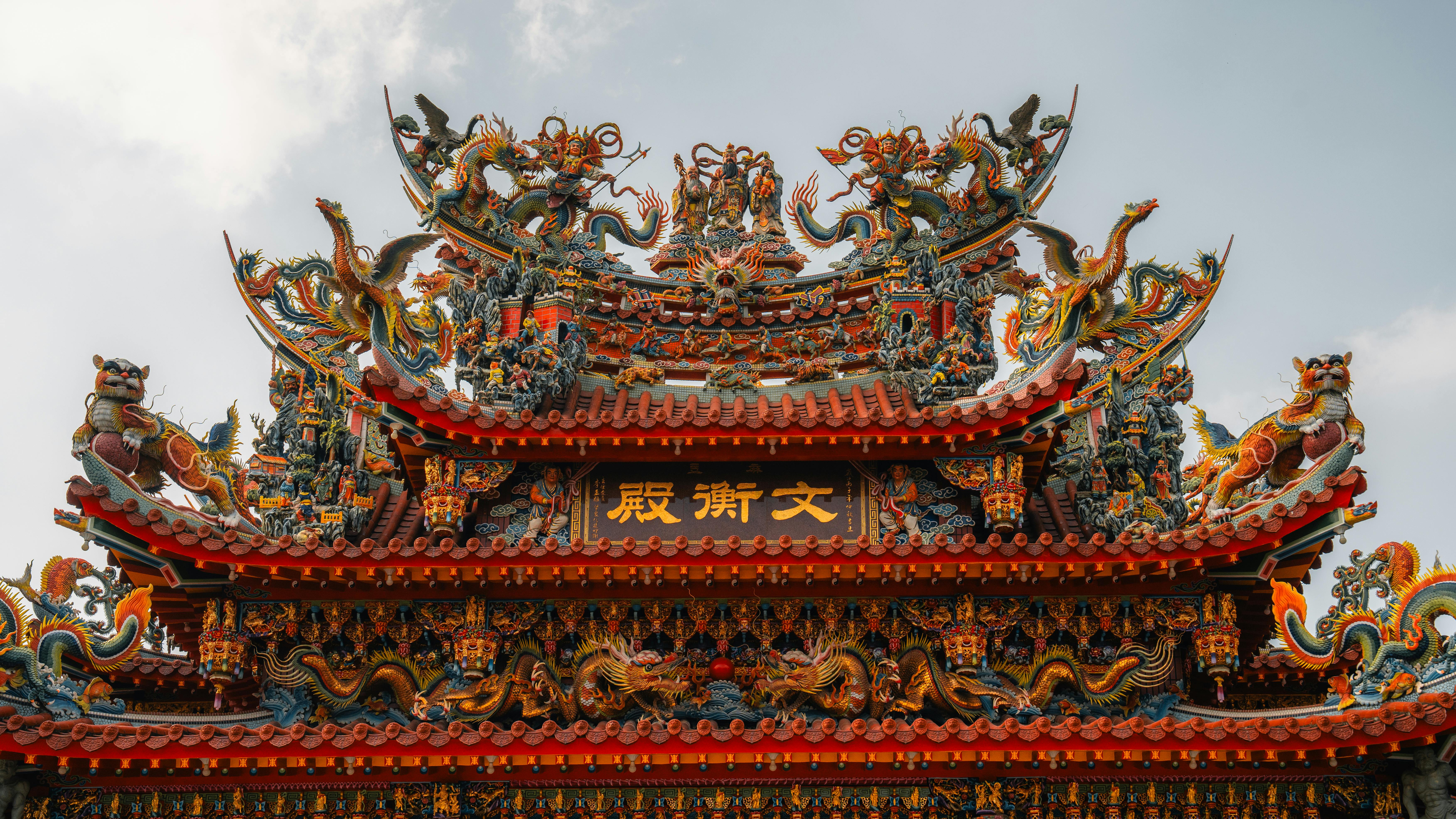 Close-up view of ornate temple roof adorned with dragons and detailed sculptures under a clear sky.