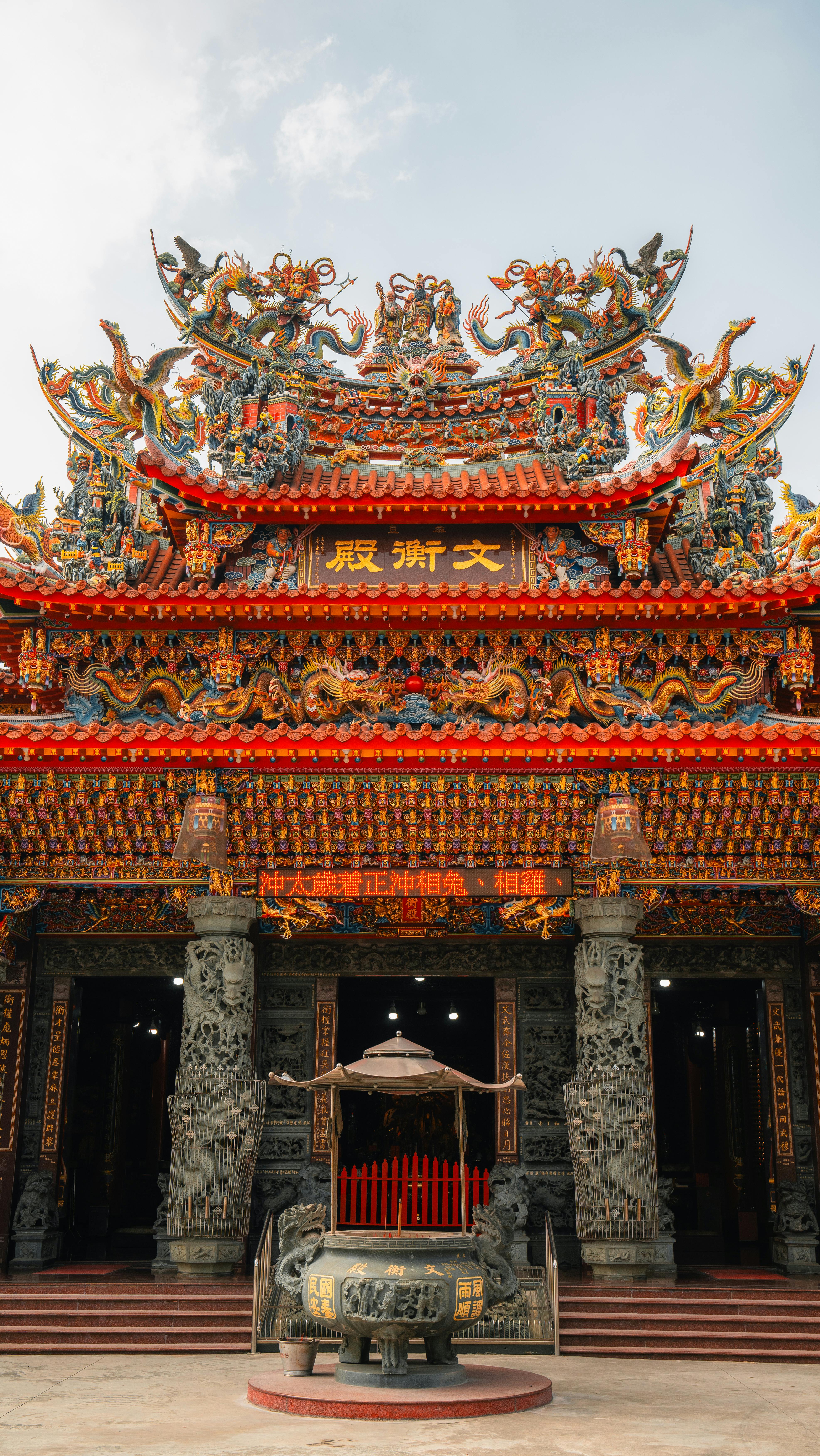 Intricately ornamented Buddhist temple facade with vibrant red roof and dragon sculptures.