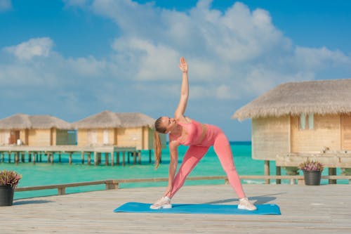 Woman in Pink Sportswear Stretching on Tropical Sea Shore