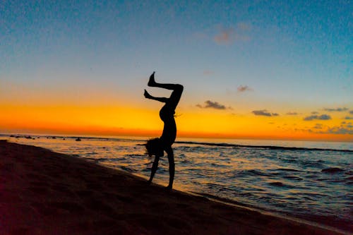 Person in Handstand on Sea Shore at Sunset