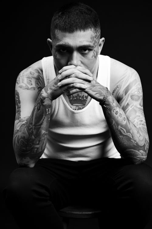 A man with tattoos sitting on a stool