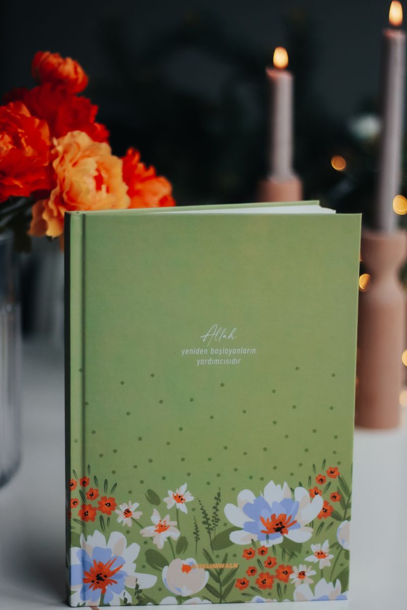 en grön bok med blommor och ljus