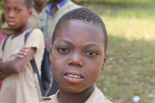Free Close-up portrait of a young boy outdoors in Togoville, providing an authentic glimpse of life in Togo. Stock Photo