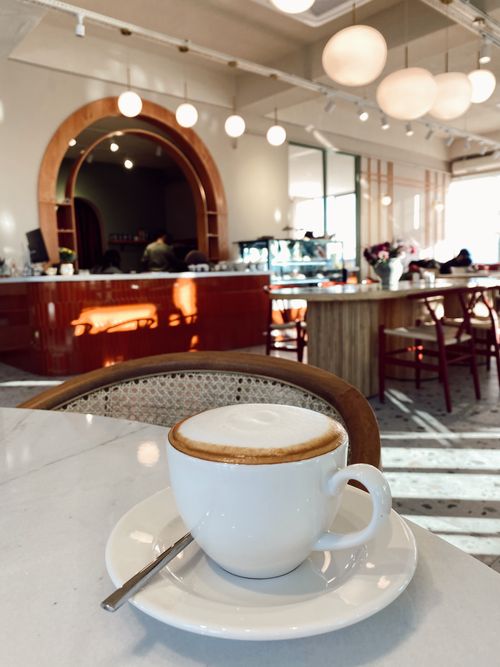 Free A fresh cappuccino on a marble table in a stylish, modern cafe with warm lighting. Stock Photo