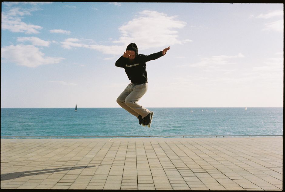 A person in a hoodie jumping on a coastal promenade by the ocean. Bright day.