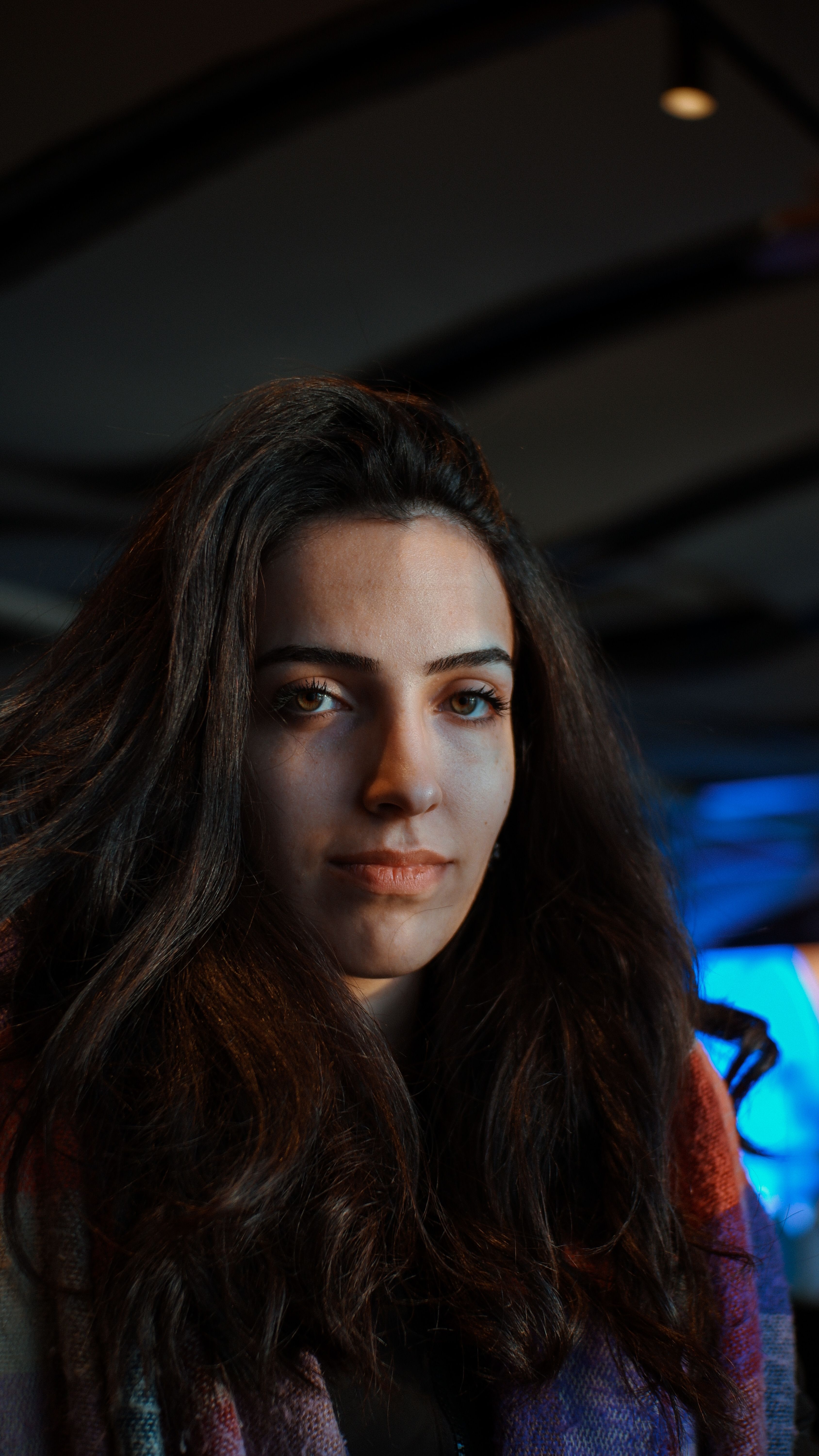 A captivating portrait of a woman with long dark hair indoors, with soft warm lighting.
