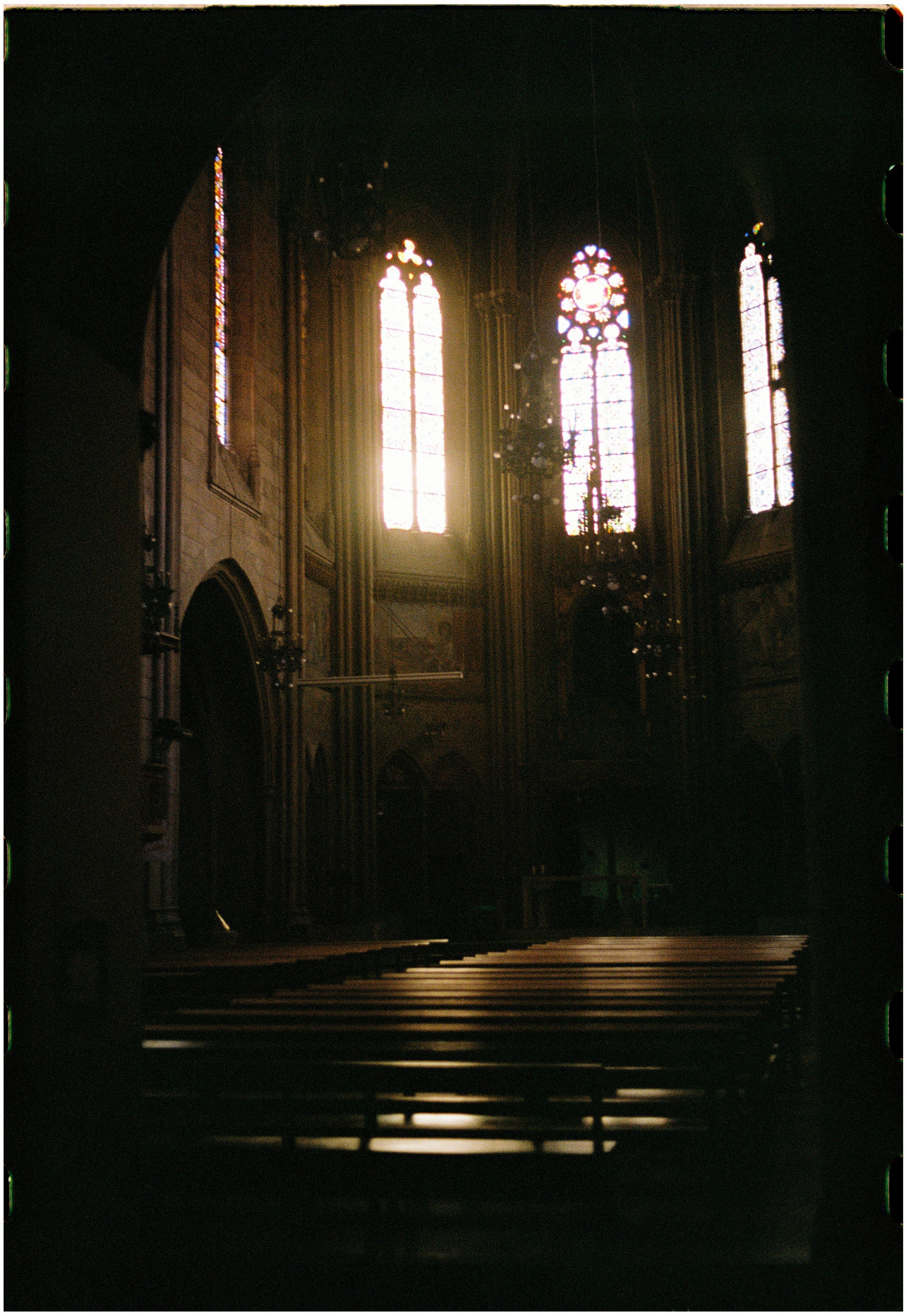 Atmospheric gothic cathedral interior with pews and stained glass windows casting a mystical light.