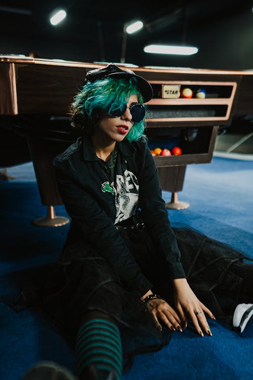 A woman with green hair sitting on the floor