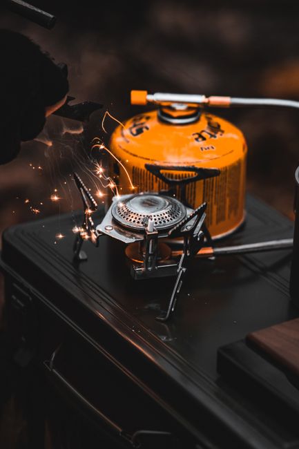 Primus Kinjia two-burner camping stove on a picnic table with cookware and ingredients