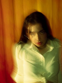 Abstract portrait of woman in white shirt with blurred artistic effect and warm tones.